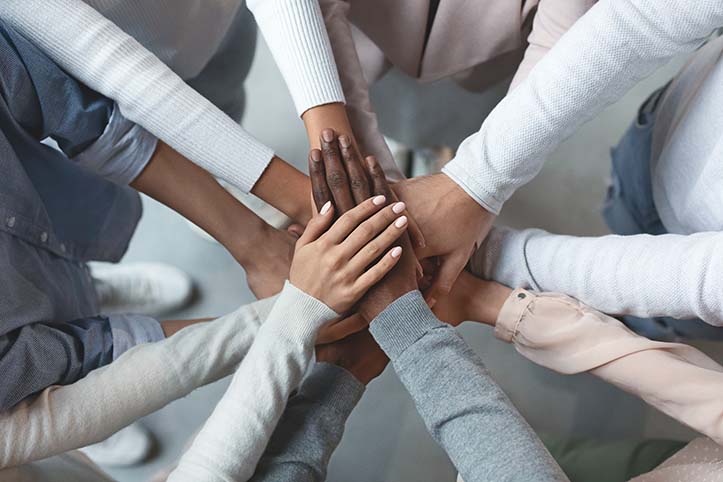 Photograph of people placing their hands on together